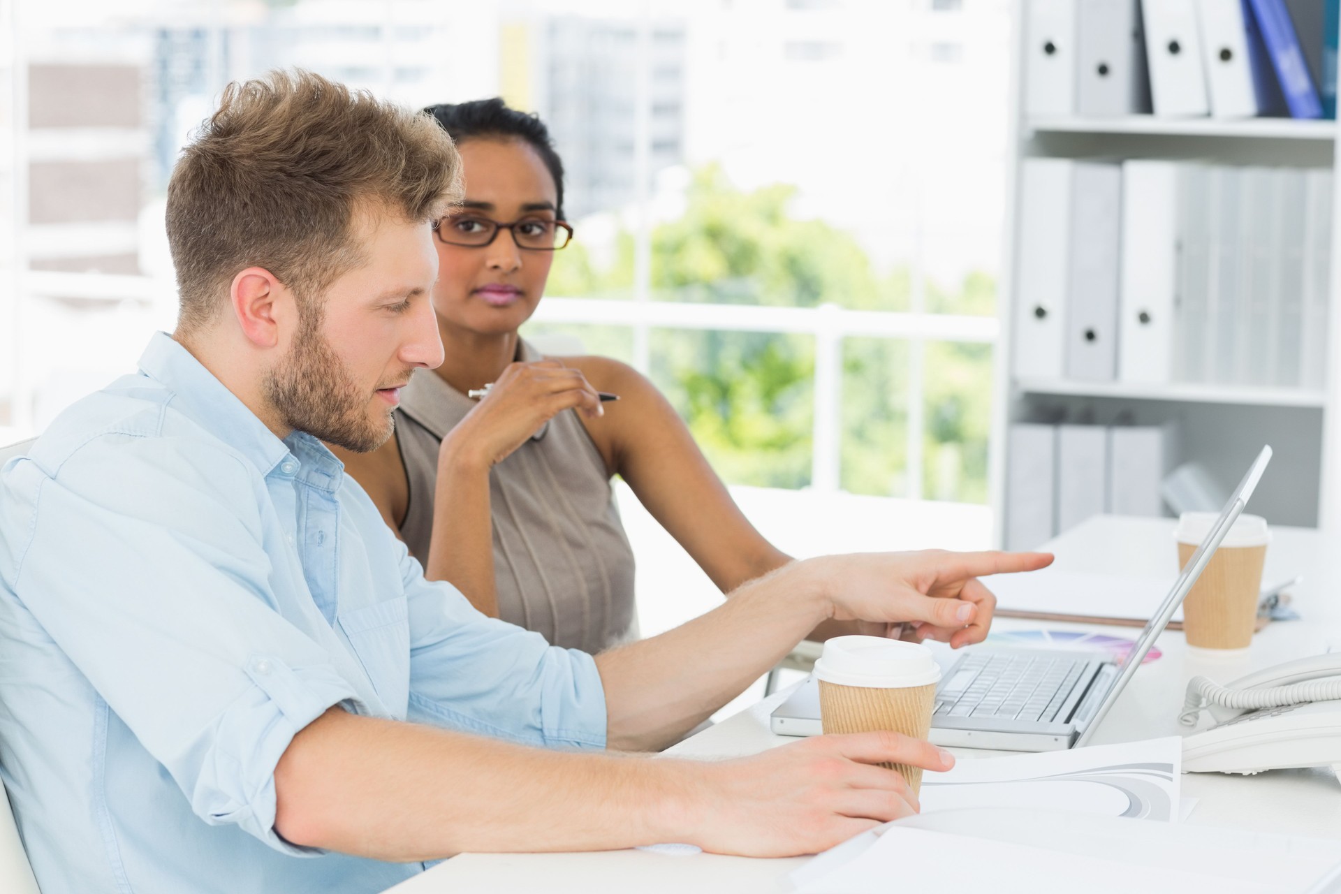 Partenaires commerciaux occasionnels travaillant ensemble sur un ordinateur portable au bureau